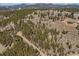 Scenic aerial capture of houses nestled in a tree-filled mountain, highlighting a tranquil, nature-integrated residential setting at 12672 Rancho Ct, Conifer, CO 80433