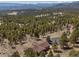 Stunning aerial view of a wooded property with a charming house nestled among tall pine trees and mountains in the background at 12672 Rancho Ct, Conifer, CO 80433