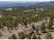 An aerial view of the property with mature trees, brown roof, and a long driveway winding through the landscape at 12672 Rancho Ct, Conifer, CO 80433