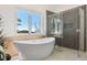 Bright bathroom featuring a modern soaking tub with a stunning mountain view and glass-enclosed shower at 12672 Rancho Ct, Conifer, CO 80433