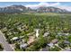 Aerial shot of a home nestled among lush trees with majestic mountains in the background on a bright, sunny day at 1270 Berea Dr, Boulder, CO 80305