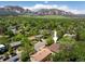 Aerial view of a home nestled among lush trees with a backdrop of majestic mountains under a bright, sunny sky at 1270 Berea Dr, Boulder, CO 80305