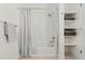 Bright bathroom featuring a bathtub with shower, gray-striped curtain, and built-in shelving for convenient storage at 2530 Lawrence St # Ra101, Denver, CO 80205