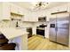 This kitchen features stainless steel appliances, white cabinets, and stone tile backsplash at 6960 E Girard Ave # 404, Denver, CO 80224