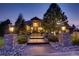 Exterior front view of a stunning home at dusk, with illuminated pathway and landscaping at 5449 Songbird Way, Parker, CO 80134
