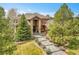 Stunning home with stone accents, a tiled roof, mature trees, and a manicured lawn and walkway at 5449 Songbird Way, Parker, CO 80134