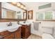 Bathroom features dual sinks with wooden cabinets, tile flooring, and framed mirrors at 6480 W 60Th Ave, Arvada, CO 80003