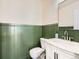 Charming half bath features green wainscoting, white vanity, and modern fixtures at 16564 High Desert Way, Parker, CO 80134