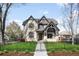 Elegant two-story home featuring a manicured lawn, iron fencing, and stone and brick accents at 2495 S Madison St, Denver, CO 80210