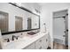 Bathroom features a double sink vanity, a black framed mirror, and an adjacent shower and bath space at 2495 S Madison St, Denver, CO 80210
