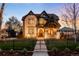 Charming two-story home with stone accents, manicured lawn, and wrought iron fence at dusk at 2495 S Madison St, Denver, CO 80210