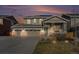 Inviting two-story home featuring a three-car garage, covered porch, stone accents, and solar panels on the roof at 6021 Lynx Creek Cir, Erie, CO 80516