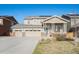 Inviting two-story home featuring a three-car garage, covered porch, stone accents, and solar panels on the roof at 6021 Lynx Creek Cir, Erie, CO 80516