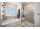 Bright bathroom with a tiled shower, bathtub, and decorative shelving with a sunny window at 6021 Lynx Creek Cir, Erie, CO 80516