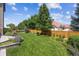 Manicured fenced backyard with verdant lawn, mature trees, and landscaped planter beds at 3890 Tabor Ct, Wheat Ridge, CO 80033