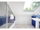 This bathroom features a skylight, blue and white tiled trim, a glass shower door, a white pedestal sink, and tiled flooring at 3375 W 37Th Ave, Denver, CO 80211