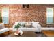 Bright living room featuring a brick wall, hardwood floors and a neutral-toned sofa at 3375 W 37Th Ave, Denver, CO 80211