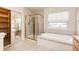 Bright bathroom featuring a bathtub, shower with gold trim, and linen closet at 5685 Columbine Ridge Rd, Elizabeth, CO 80107