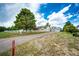 Exterior view of this charming property featuring a large tree, white fencing, lush greenery, and a spacious driveway at 5685 Columbine Ridge Rd, Elizabeth, CO 80107