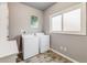 Well-lit laundry room with white washer and dryer units, storage, and neutral wall color at 236 E Fair Ln, Centennial, CO 80121