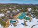 Aerial view showcasing community amenities with pool, tennis courts, parking, and mountain views in winter at 30544 The Golf Club Point, Evergreen, CO 80439