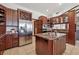 Well-equipped kitchen with stainless steel refrigerator, wine rack, central island with sink, and custom cabinetry at 30544 The Golf Club Point, Evergreen, CO 80439