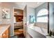Bright bathroom featuring a bathtub, granite-topped vanity, and views into the main bedroom at 20341 E 48Th Pl, Denver, CO 80249