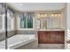 Bathroom featuring double sinks and an enclosed bath tub under a sunlit window at 8489 S Quay St, Littleton, CO 80128