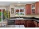 Kitchen features dark cabinets, black countertop, stainless sink and floral curtains at 8489 S Quay St, Littleton, CO 80128