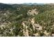 This aerial shot showcases homes in a sprawling forest, highlighting a mix of seclusion and community at 7290 Timber Trail Rd, Evergreen, CO 80439