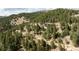 An aerial view showcases the home in a forest setting, providing a sense of peaceful seclusion and natural beauty at 7290 Timber Trail Rd, Evergreen, CO 80439