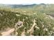 An aerial view of a mountain home nestled among trees and a natural landscape in a mountainous area at 7290 Timber Trail Rd, Evergreen, CO 80439