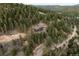 An aerial view shows a home among green trees along a road, revealing a tranquil and secluded location at 7290 Timber Trail Rd, Evergreen, CO 80439
