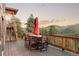 Wooden deck with table and chairs and forest views at 7290 Timber Trail Rd, Evergreen, CO 80439