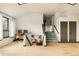 Large living area with hardwood floors, multiple doors, and a staircase with gray carpet at 7290 Timber Trail Rd, Evergreen, CO 80439