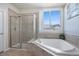 Bright bathroom with a glass-enclosed shower and soaking tub under a window at 10071 E 142Nd Ave, Brighton, CO 80602
