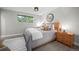 Bright bedroom with a modern round mirror, bedside table, and a cozy, textured gray and white bedspread at 794 W Elati Cir, Littleton, CO 80120