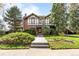 Two-story Tudor-style home featuring lush landscaping, brick and white stucco exterior and a charming green roof at 1317 Birch St, Denver, CO 80220