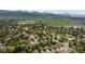 A wide aerial shot shows a neighborhood with homes, trees and green spaces and mountains in the distance at 7176 S Pierson St, Littleton, CO 80127