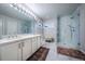 Elegant bathroom featuring double vanity and frameless glass shower with marble surround at 7176 S Pierson St, Littleton, CO 80127