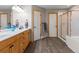 Bright bathroom featuring wood cabinets, double doors, shower, and tile flooring at 15652 W 79Th Pl, Arvada, CO 80007