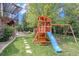 Spacious backyard with play structure, mature trees, and pathway to stone patio for outdoor enjoyment at 21416 E Ottawa Cir, Aurora, CO 80016