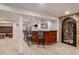 Basement bar with dark wood, granite counter, seating, and a stone-accented doorway to the wine cellar at 21416 E Ottawa Cir, Aurora, CO 80016