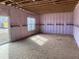 Unfinished living room with pink insulation, exposed wood and a sliding glass door to the backyard at 15296 Fillmore St, Thornton, CO 80602