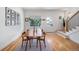 Elegant dining area with a wooden table, stylish chairs, and hardwood floors, complemented by a staircase and artwork at 2571 S Cherokee St, Denver, CO 80223