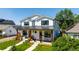 Inviting two-story house boasts a charming porch with seating and meticulously maintained landscaping in a bright, sunny setting at 2571 S Cherokee St, Denver, CO 80223