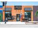 Eye-catching orange building with murals, black awnings, and ample street-side seating at 2571 S Cherokee St, Denver, CO 80223