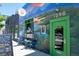 Stylish building exterior with a green door, mural, and sidewalk seating at 2571 S Cherokee St, Denver, CO 80223