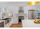 Bright kitchen with stainless steel appliances, farmhouse sink, white cabinets, and light countertops at 2571 S Cherokee St, Denver, CO 80223