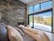 Bedroom with a stone wall, fireplace, and large windows showcasing mountain views at 132 N Gold Flake Ter, Breckenridge, CO 80424